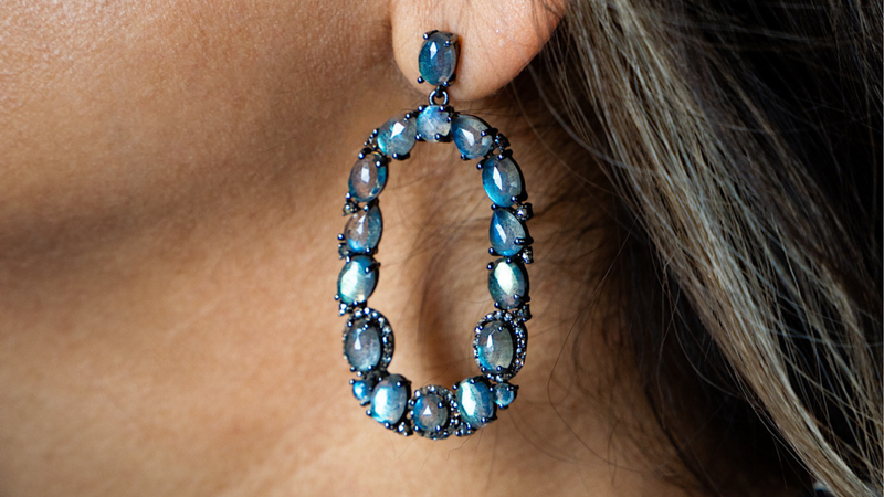 Earring with Labradorite beads on a dark blue background with text about Labradorite vs Moonstone properties.