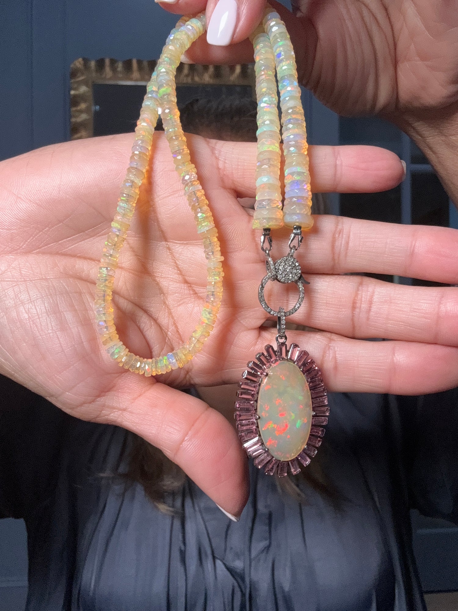 18.5-inch Ethiopian opal beaded necklace with plum tourmaline-framed opal pendant and diamond clasp held in hands, showing iridescent rainbow fire flashes