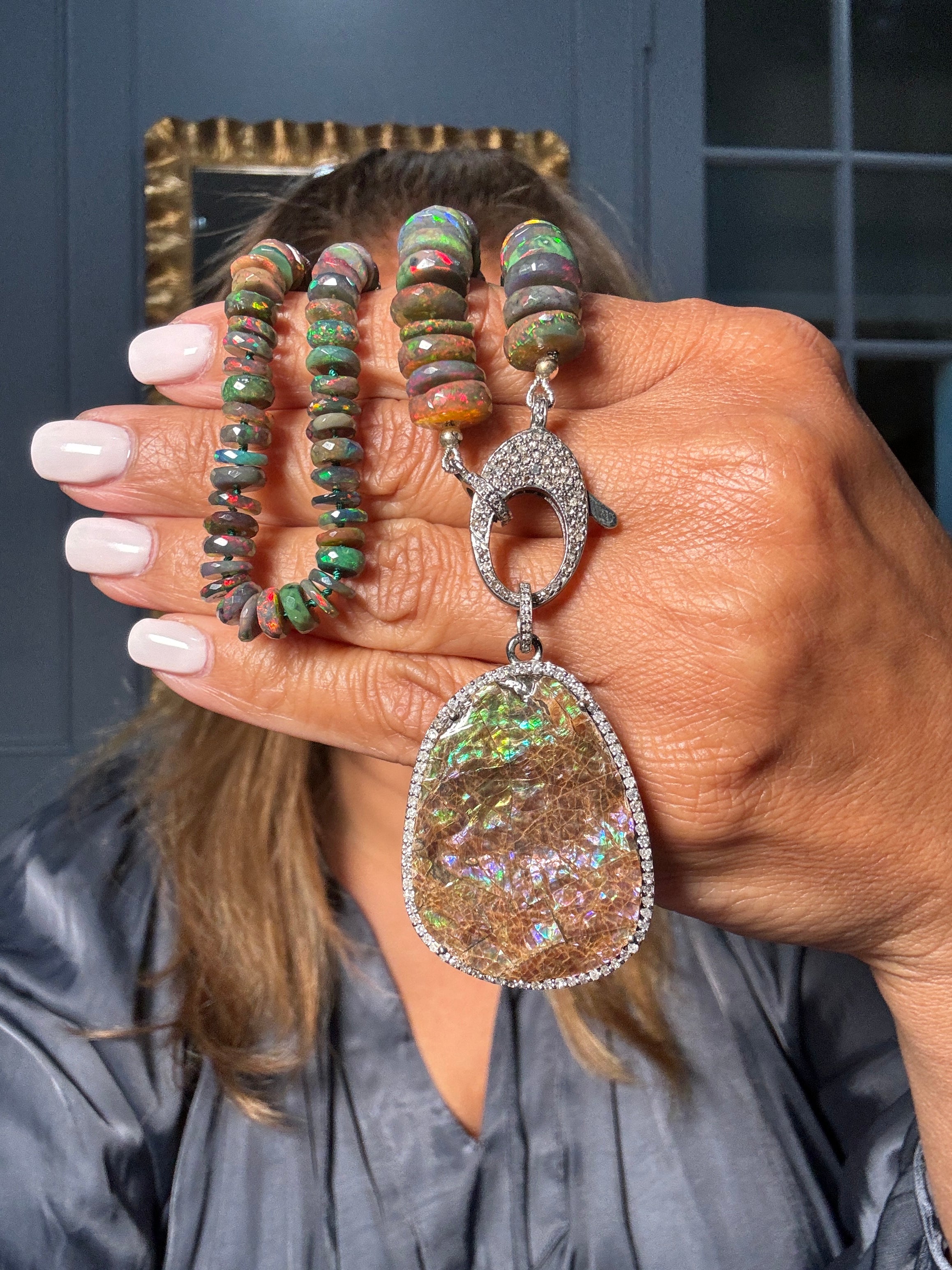 Ulka Rocks one-of-a-kind necklace with fiery boulder opal pendant framed in diamonds, paired with 18” strand of multi-colored black opal rondelles and sterling silver clasp.