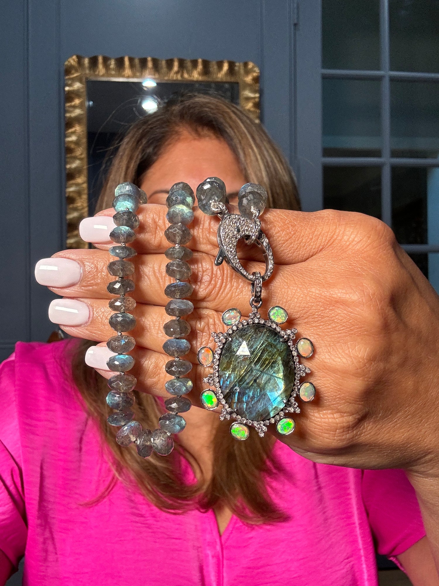 Hand holding an 18-inch labradorite bead necklace with large circular labradorite pendant surrounded by opal and diamond accents in sterling silver setting