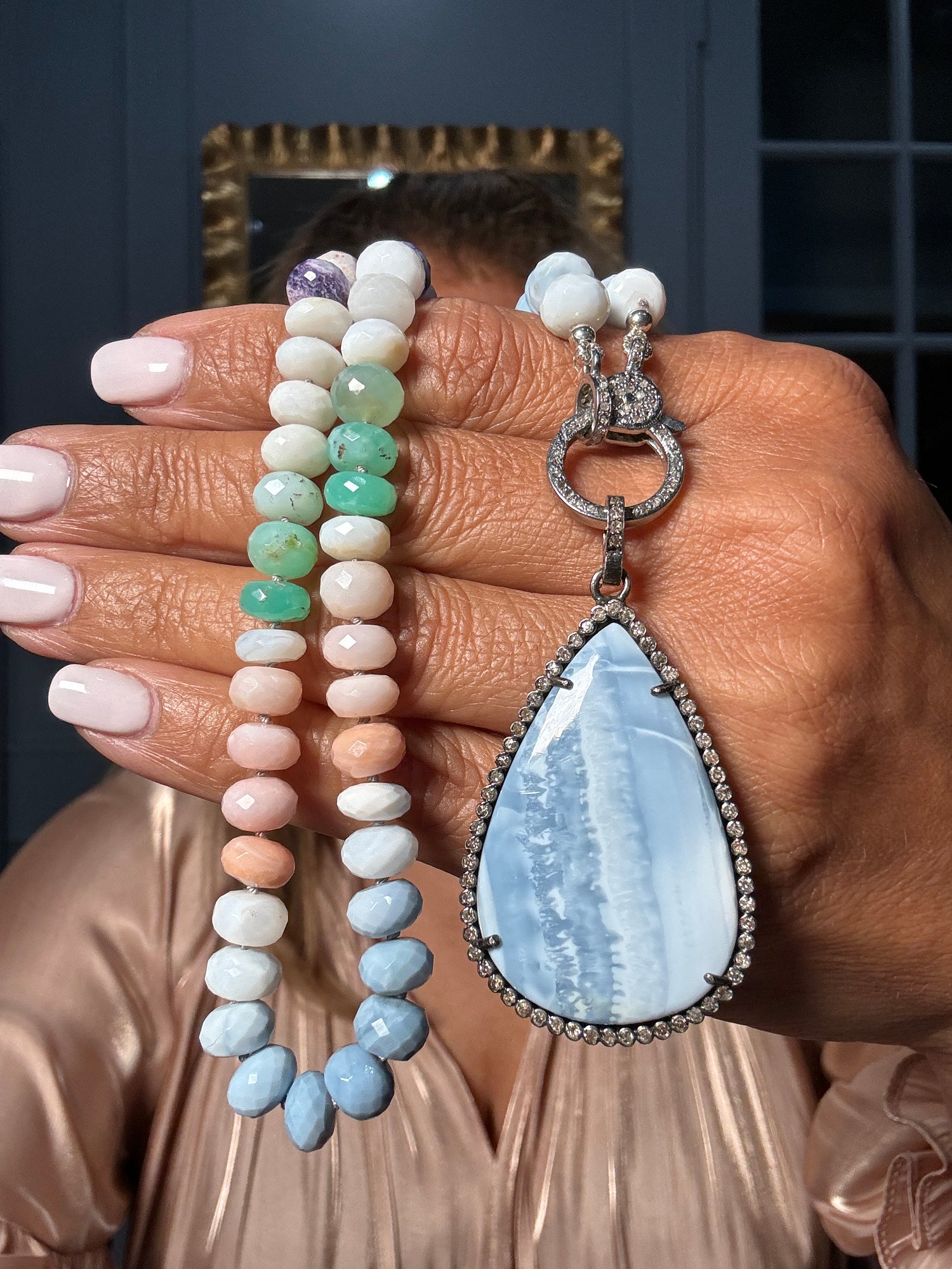 20.5-inch pastel opal necklace held in hands showing faceted white, pink, green and blue opal beads with teardrop Owyhee opal pendant in diamond-encrusted sterling silver setting