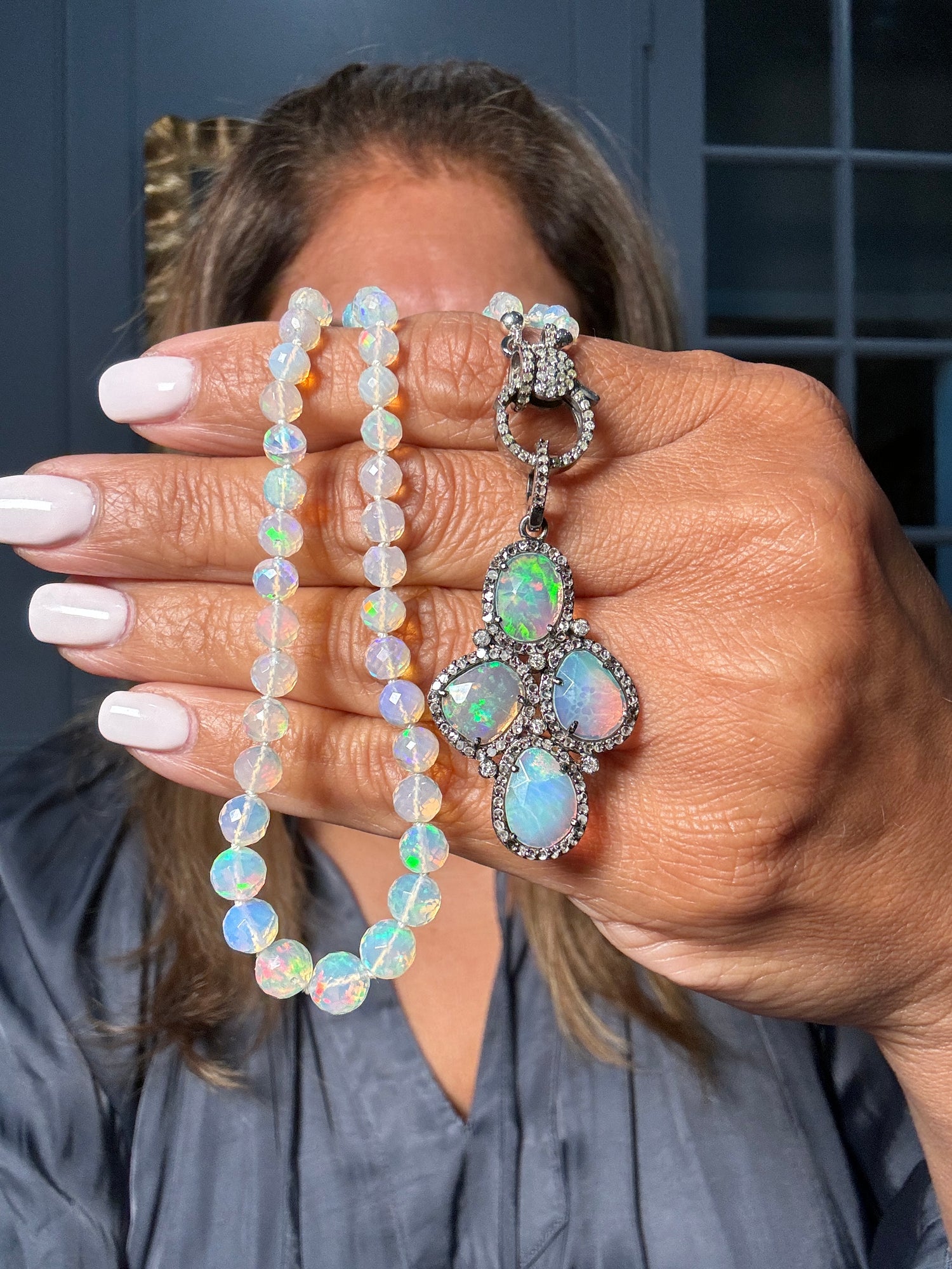 Hand displaying 20-inch Ethiopian opal beaded necklace with iridescent blue-green stones and ornate diamond-accented sterling silver pendant featuring multiple opals in geometric design