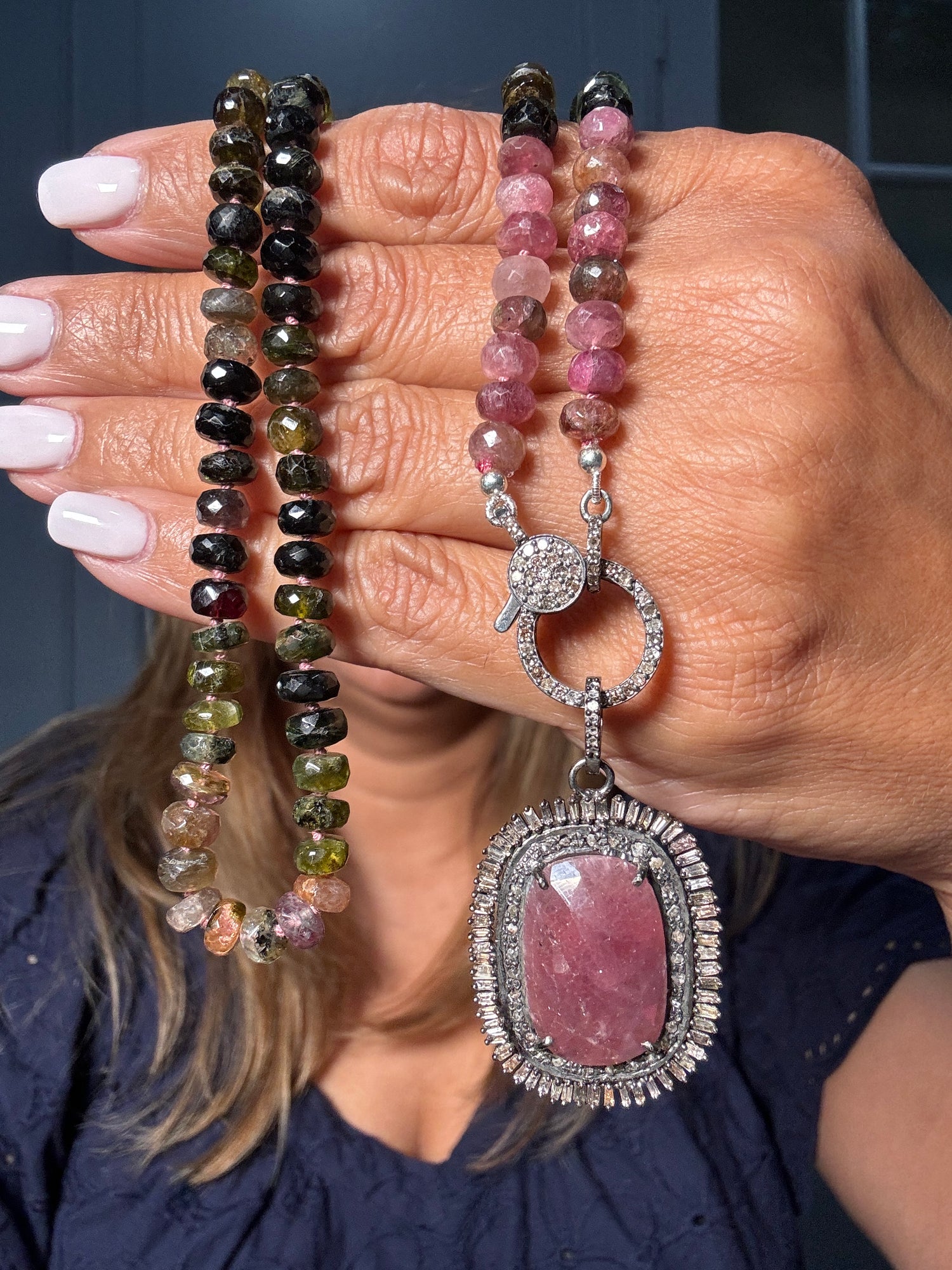 24-inch tourmaline necklace with faceted multicolored gemstone beads and ornate ruby pendant with diamond sterling silver clasp held in hand