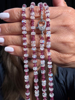 Hand holding a 34-inch necklace with alternating rhodolite garnet and moonstone beads featuring a decorative sterling silver clasp with intricate detailing.