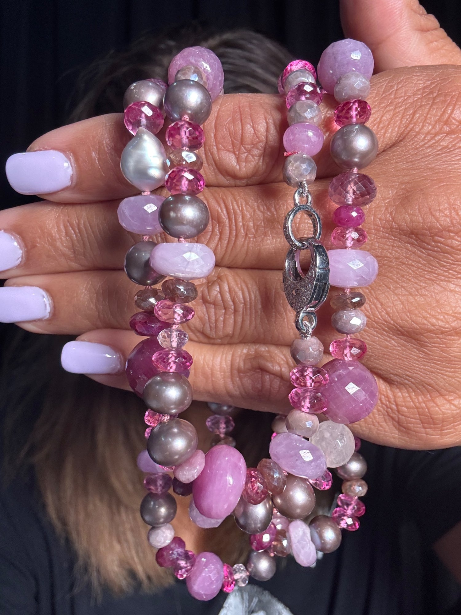 35-inch beaded necklace with pink rubies, lavender kunzite, gray pearls and pink topaz accents held in hands against person with light purple manicure