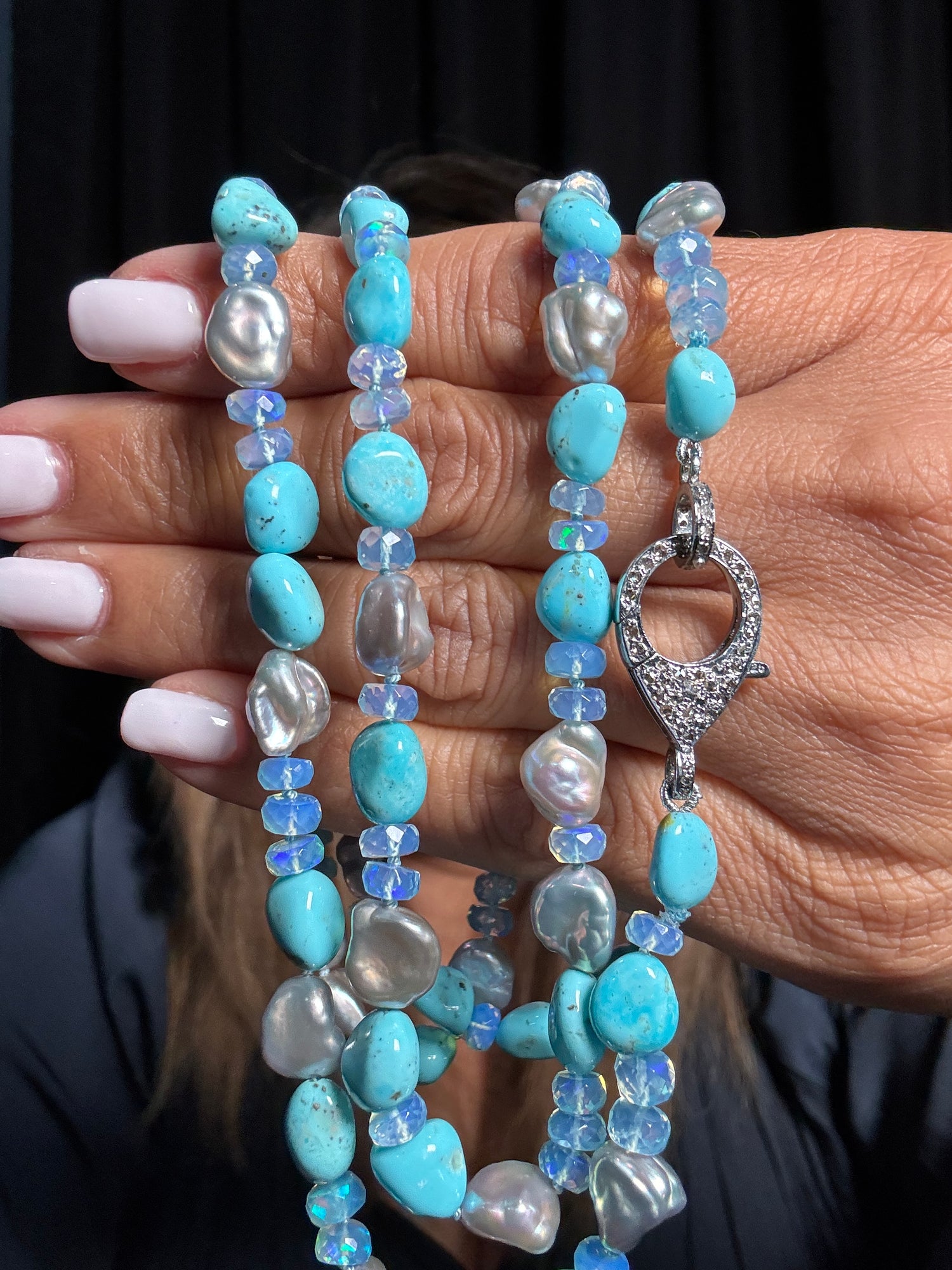 35-inch beaded necklace with turquoise opal and white keshi pearls held in hands, featuring a diamond-encrusted sterling silver toggle clasp