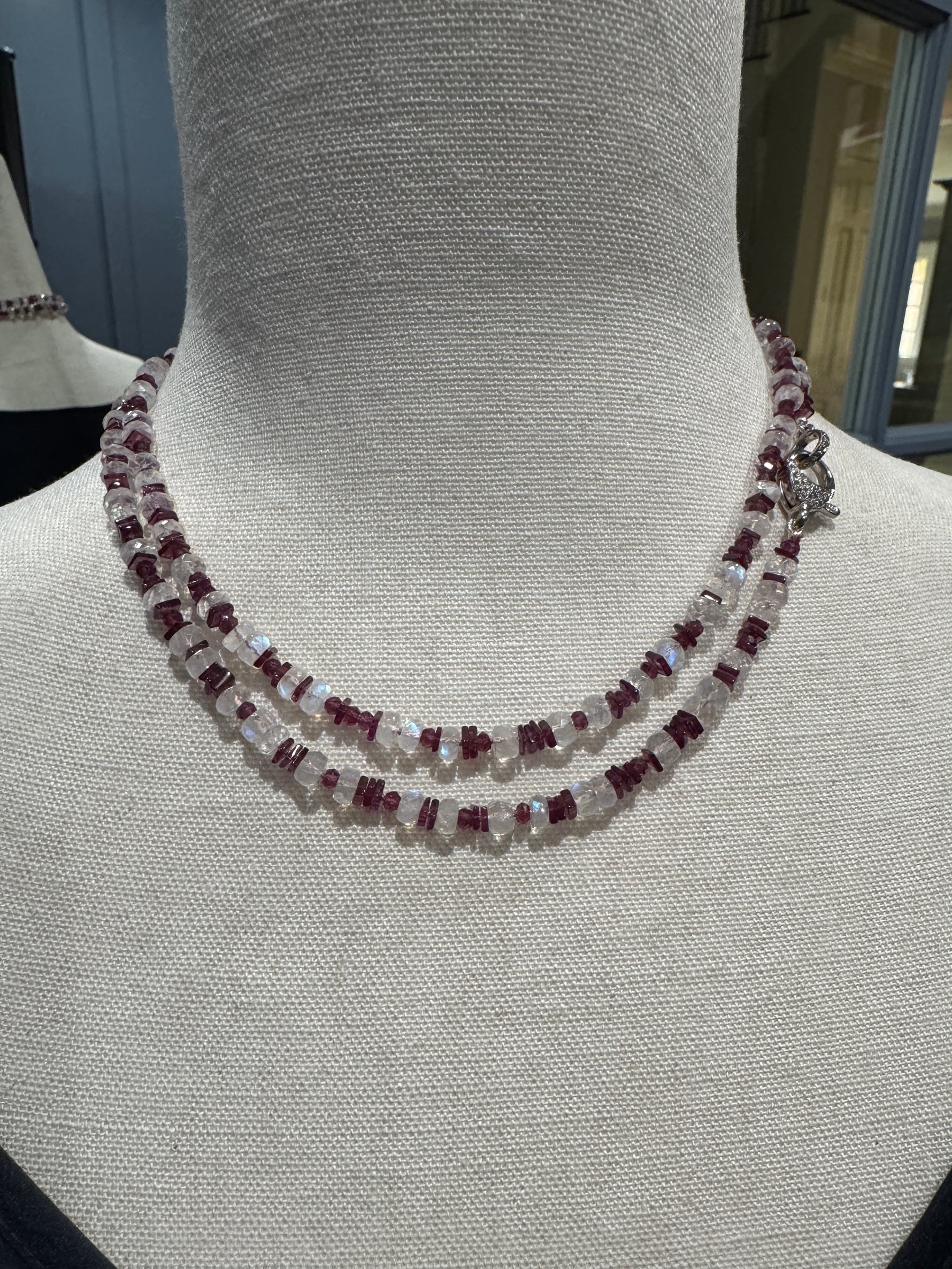 Double-strand 34-inch necklace with rhodolite garnet and moonstone beads displayed on beige mannequin, featuring sterling silver toggle clasp and graceful layered look.