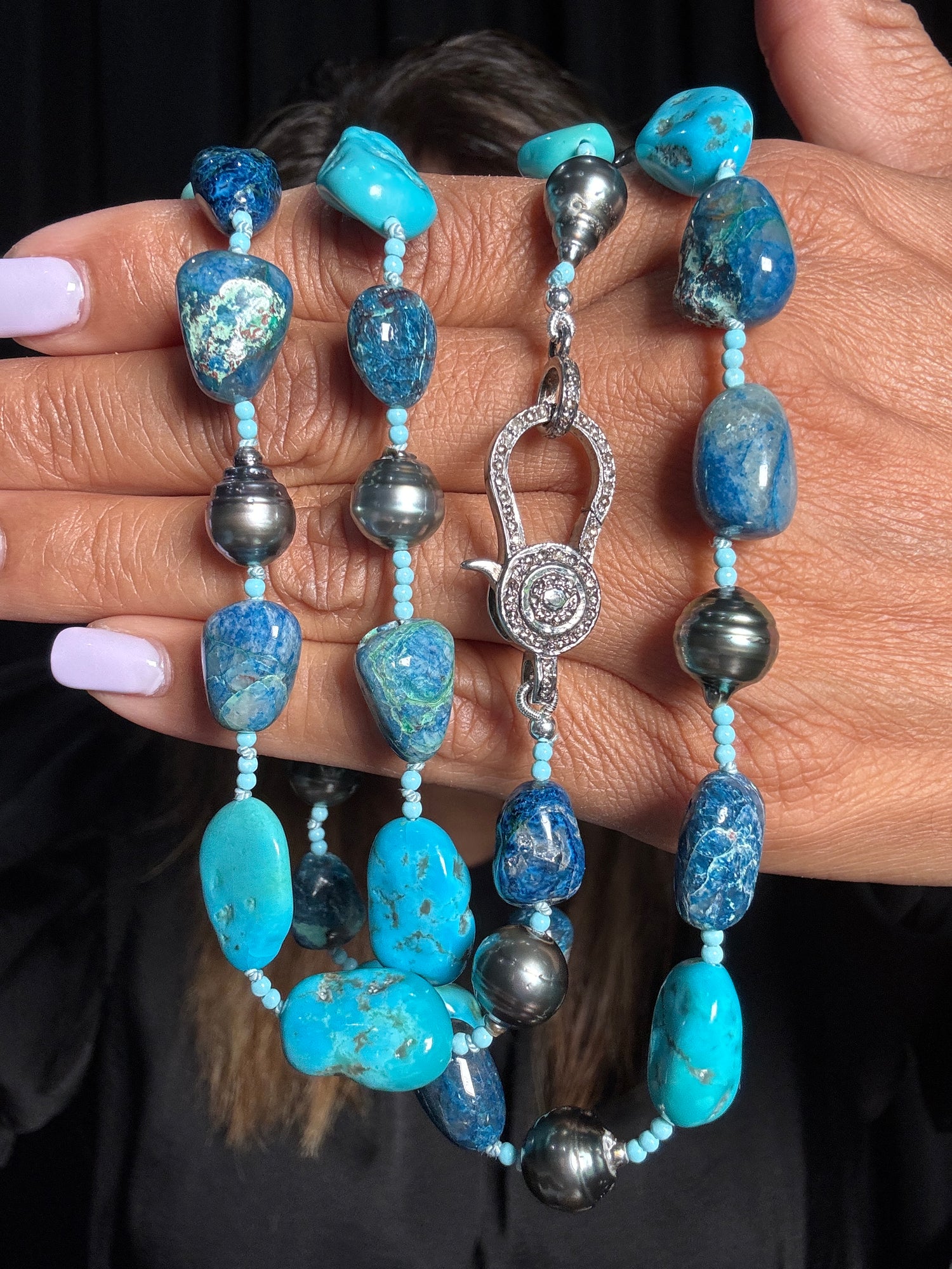 35-inch necklace with turquoise, chrysocolla, and gray Tahitian pearls held in hands, featuring ornate sterling silver diamond clasp