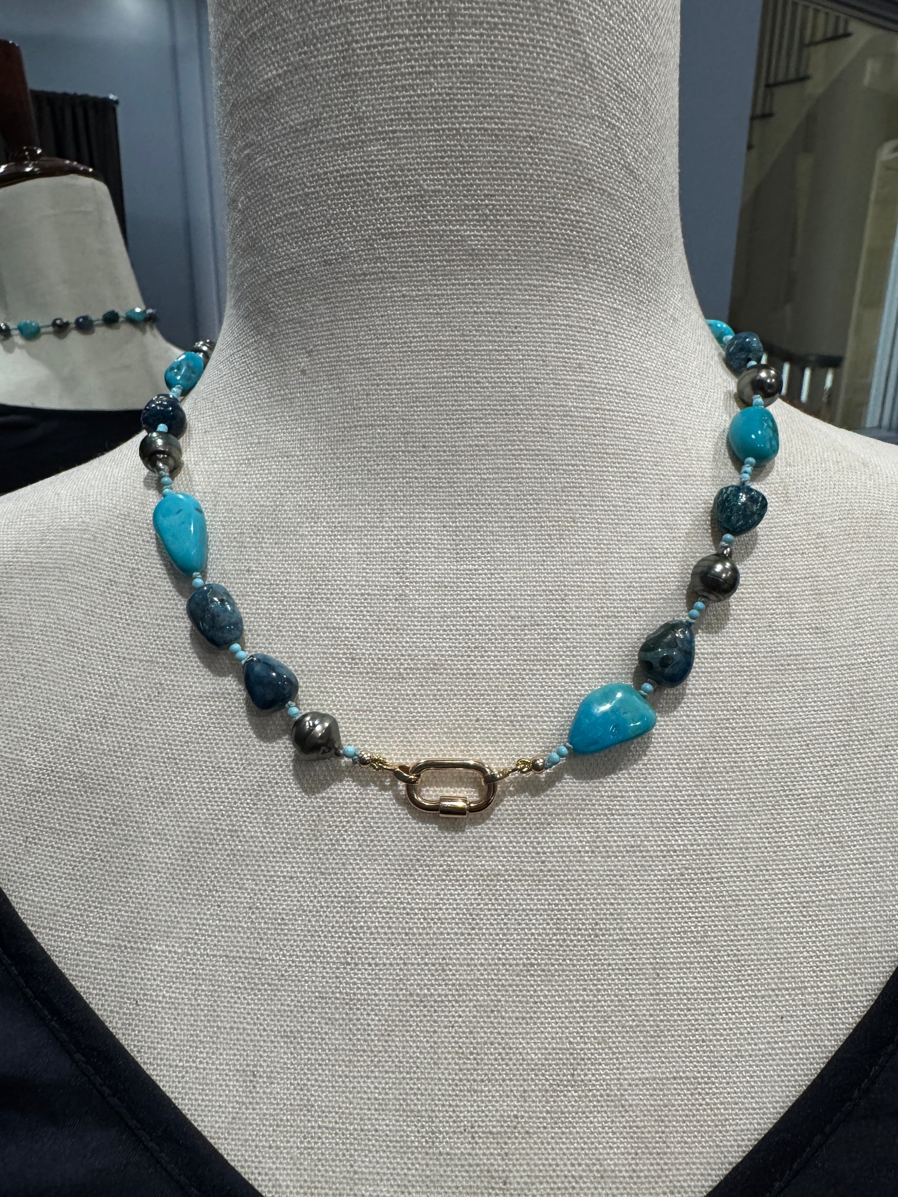 Close-up of 14k gold carabiner-style enhancer clasp on Tahitian pearl and turquoise necklace, showing how the clasp doubles as a front-facing design element