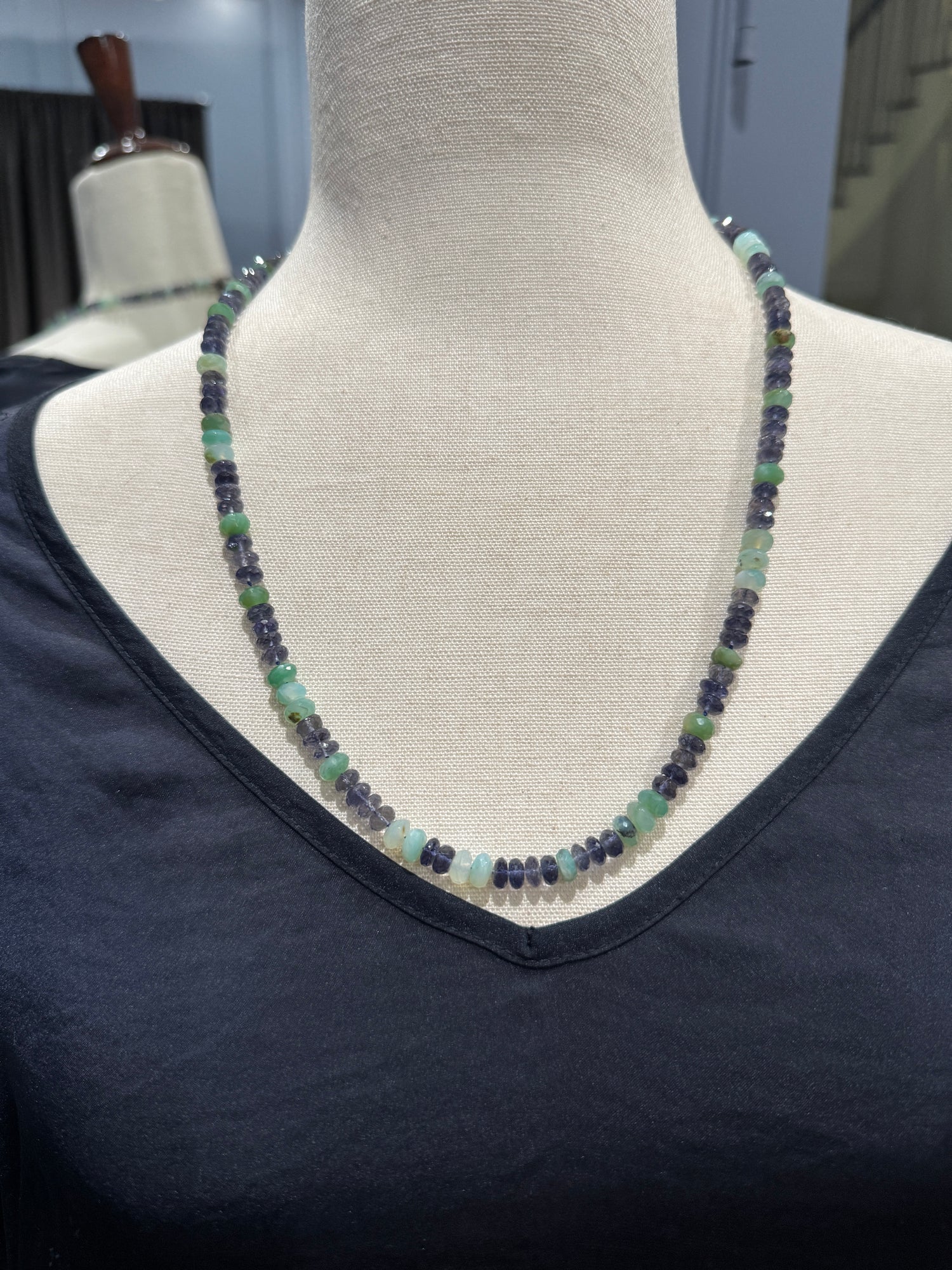 24-inch iolite and Peruvian opal necklace displayed on beige fabric mannequin, showing alternating purple and seafoam green gemstone beads in elegant drape