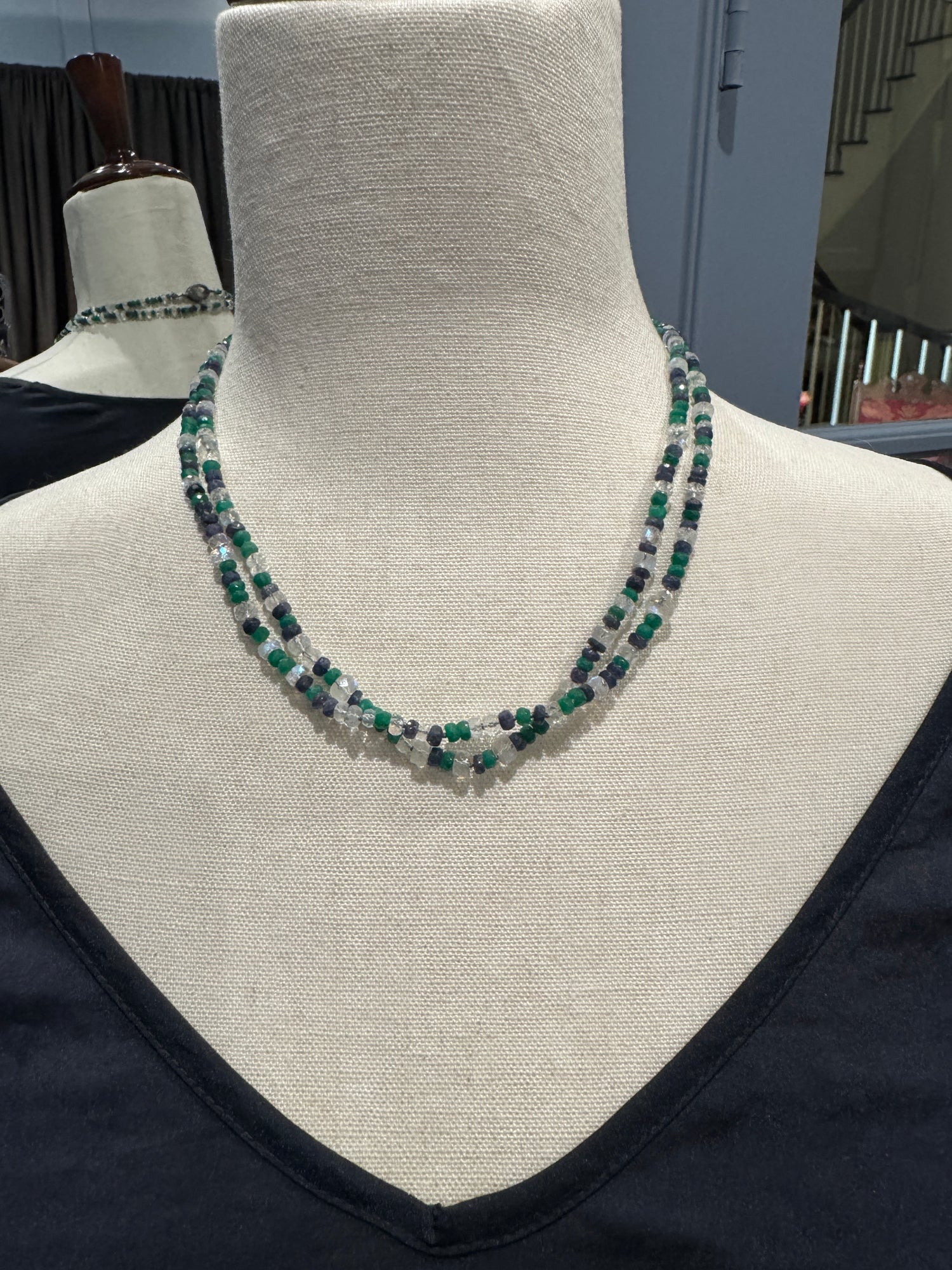 Double-strand moonstone, green onyx and blue sapphire necklace displayed on beige fabric mannequin at choker length showing mixed gemstone colors