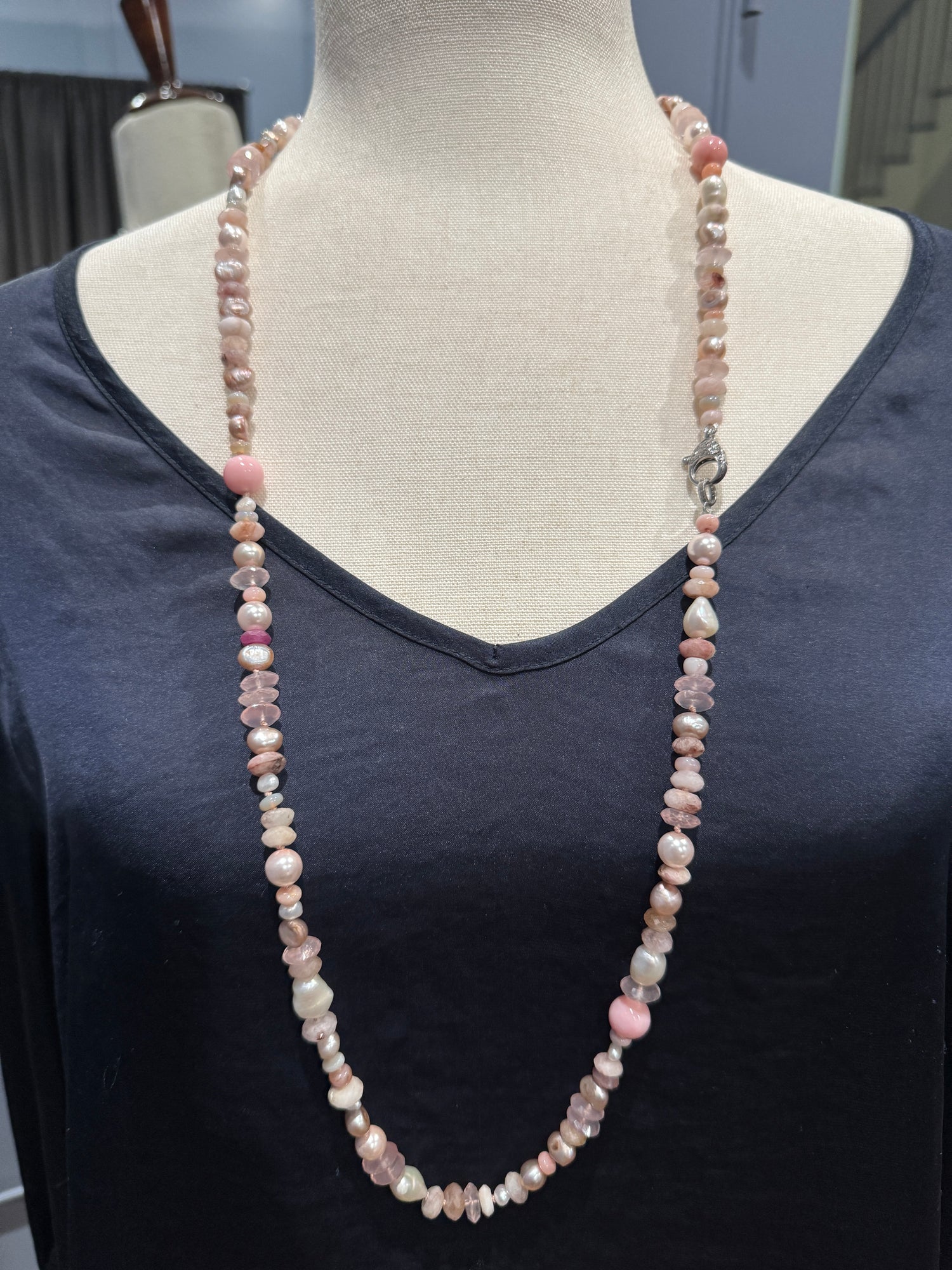 Long pink gemstone and pearl necklace displayed on cream fabric mannequin showing full 36-inch length with mixed bead sizes