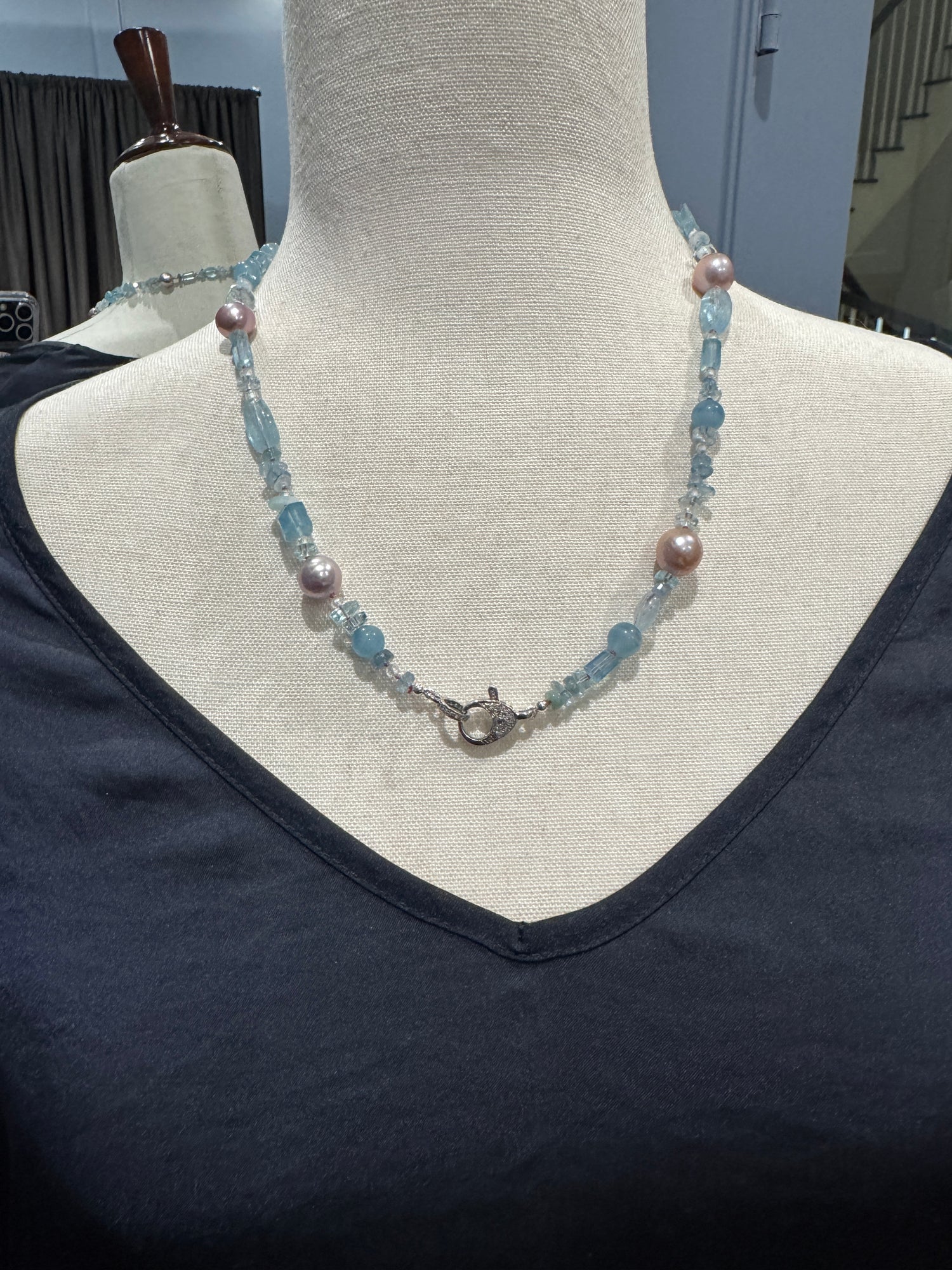Aquamarine and pink Edison pearl necklace displayed on neutral mannequin, showing mixed blue gemstone cuts and lustrous pearls in elegant drape