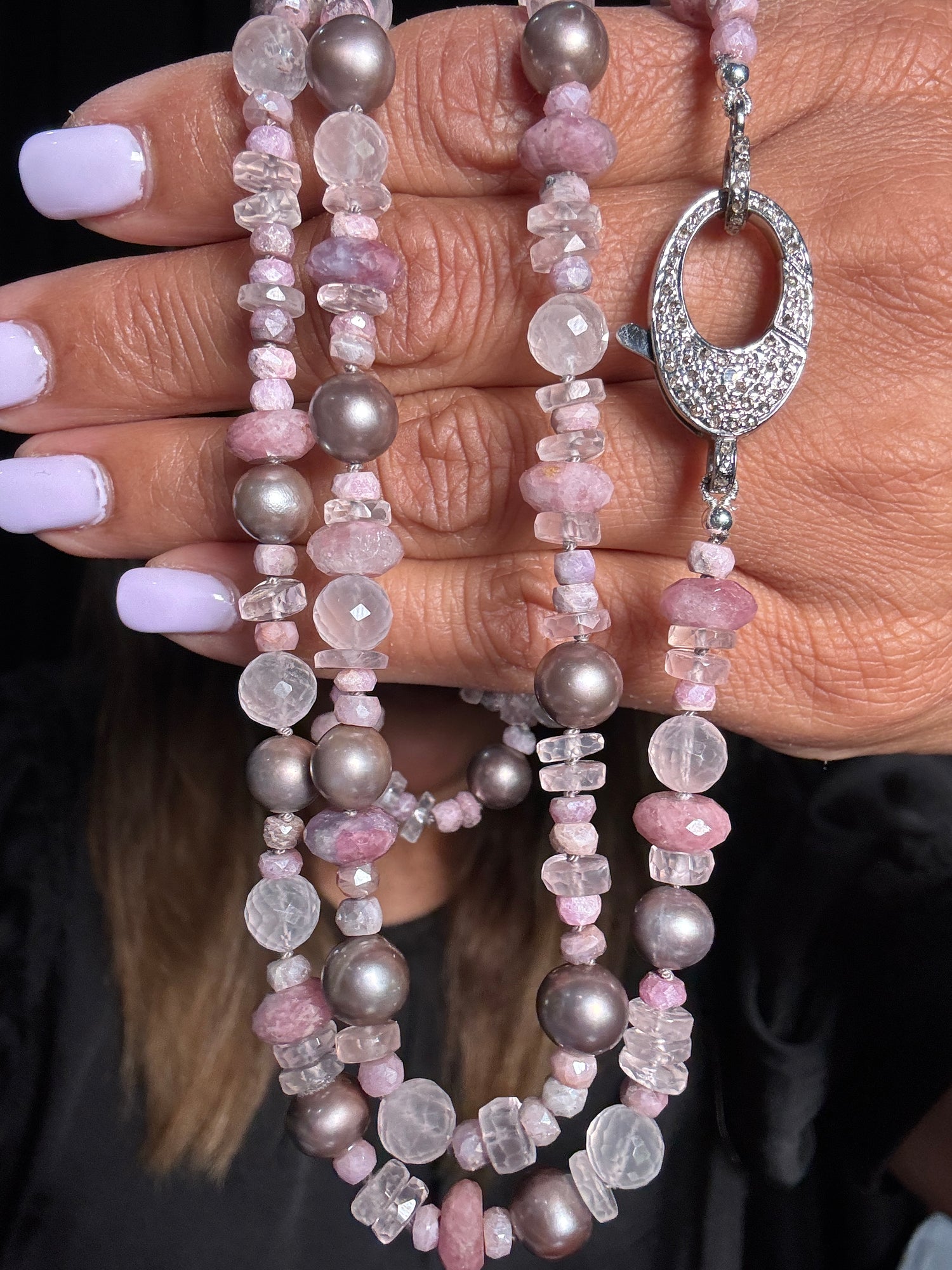 35-inch necklace with pink gemstones, clear quartz, and gray Tahitian pearls held in hands, featuring ornate silver clasp with diamonds