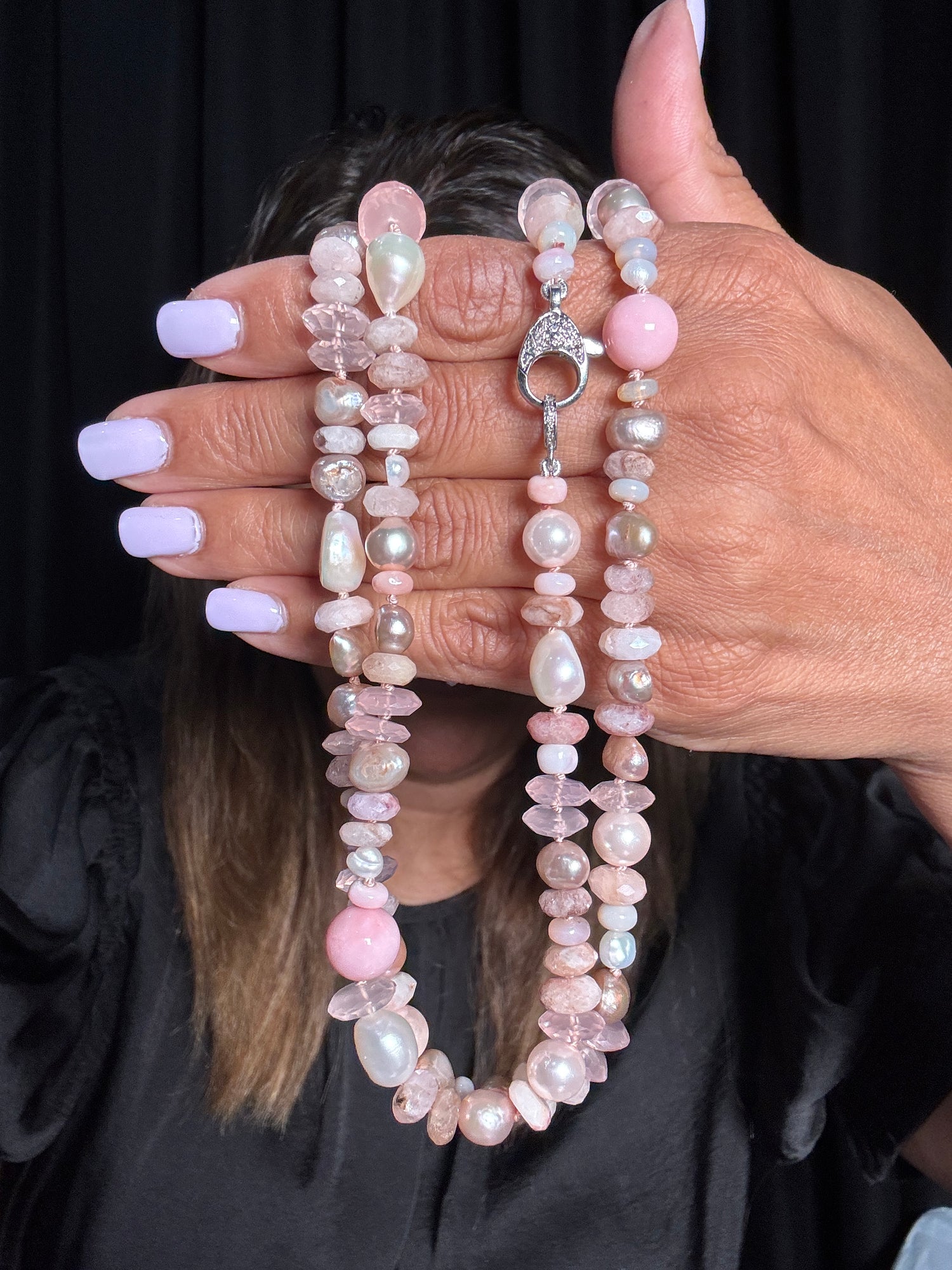 Hand holding a 36-inch necklace with pink morganite chips, white Edison pearls, and silver toggle clasp against black background