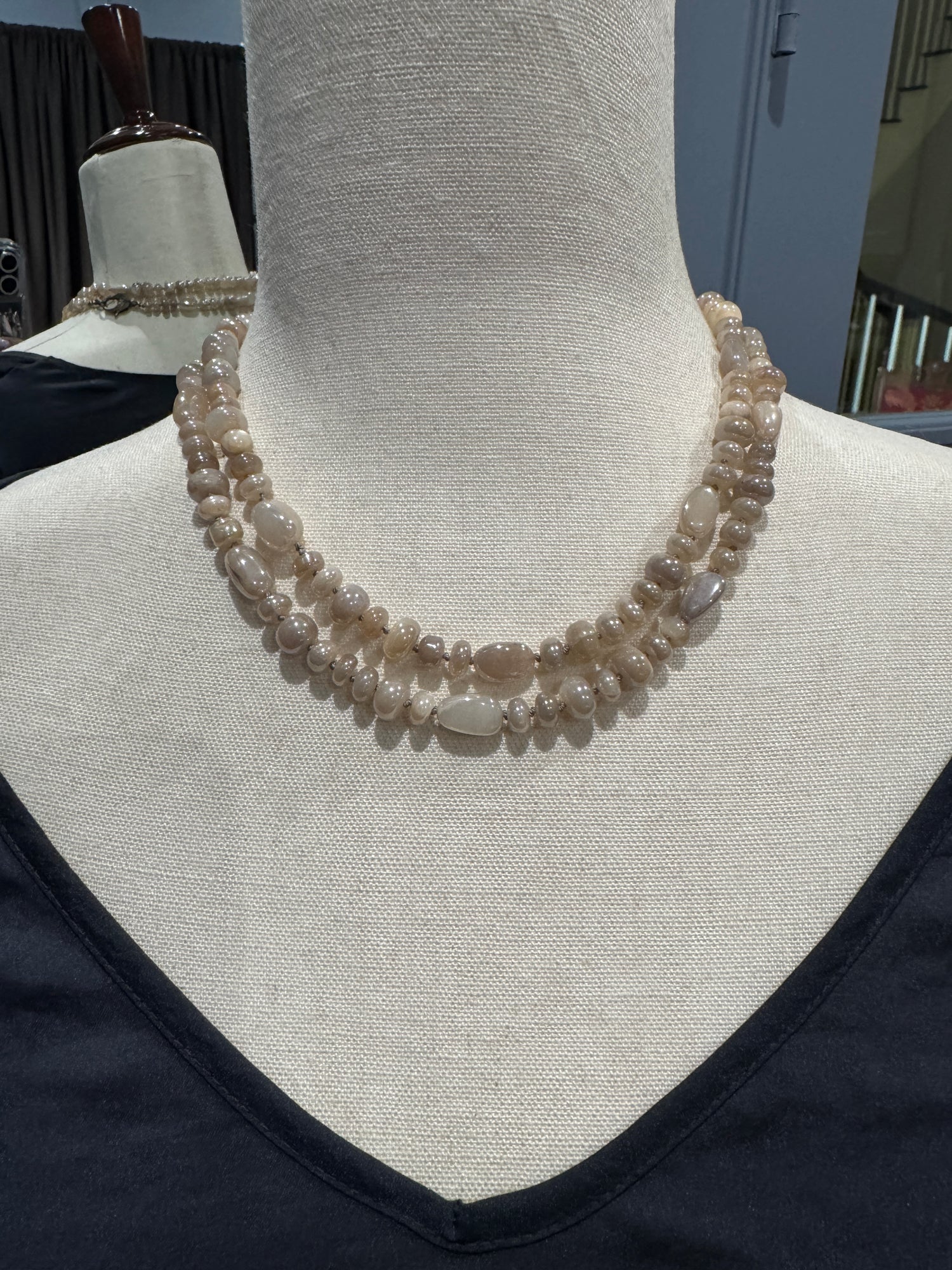 36-inch moonstone necklace displayed on cream fabric mannequin, showing double-strand layered styling with polished oval beads