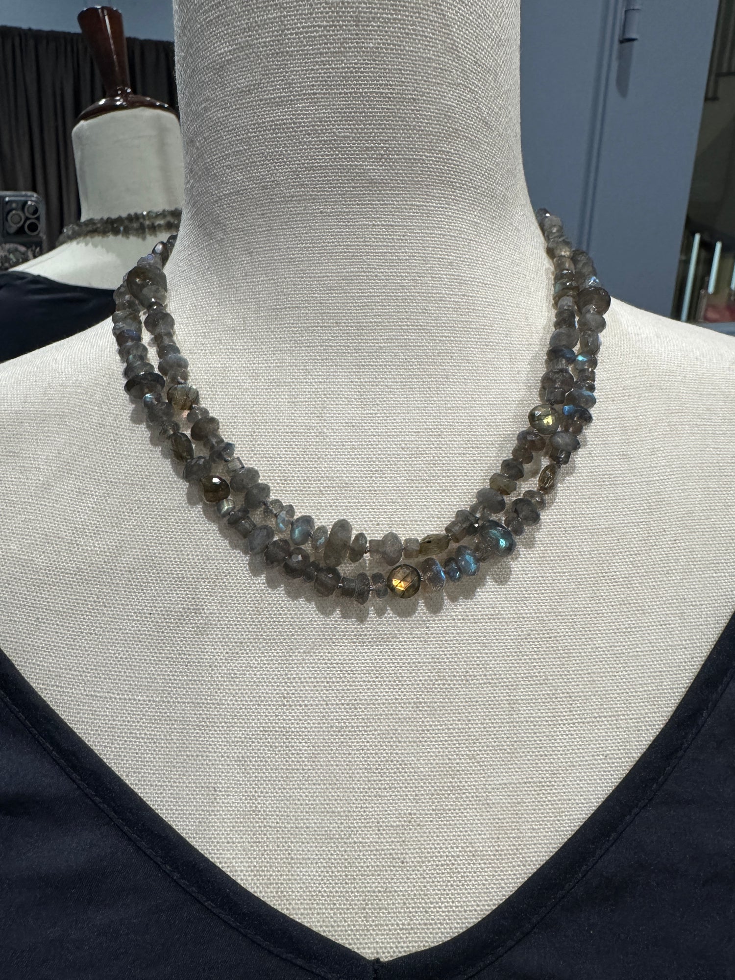 36-inch labradorite necklace displayed on cream fabric mannequin showing faceted gray stones with blue iridescent flashes