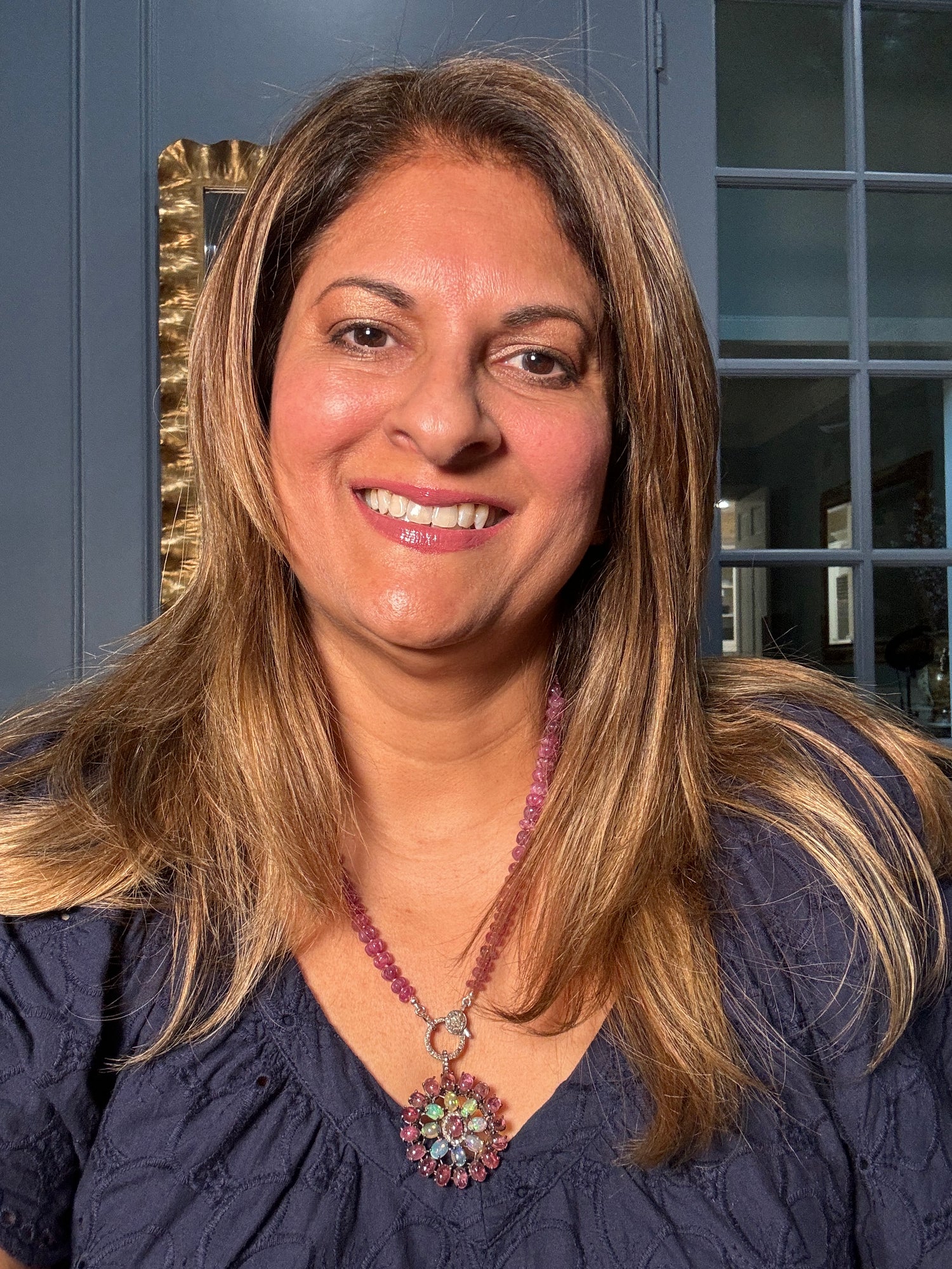 Woman wearing carved pink tourmaline necklace with opal and tourmaline flower pendant, showcasing how the 22-inch length drapes elegantly