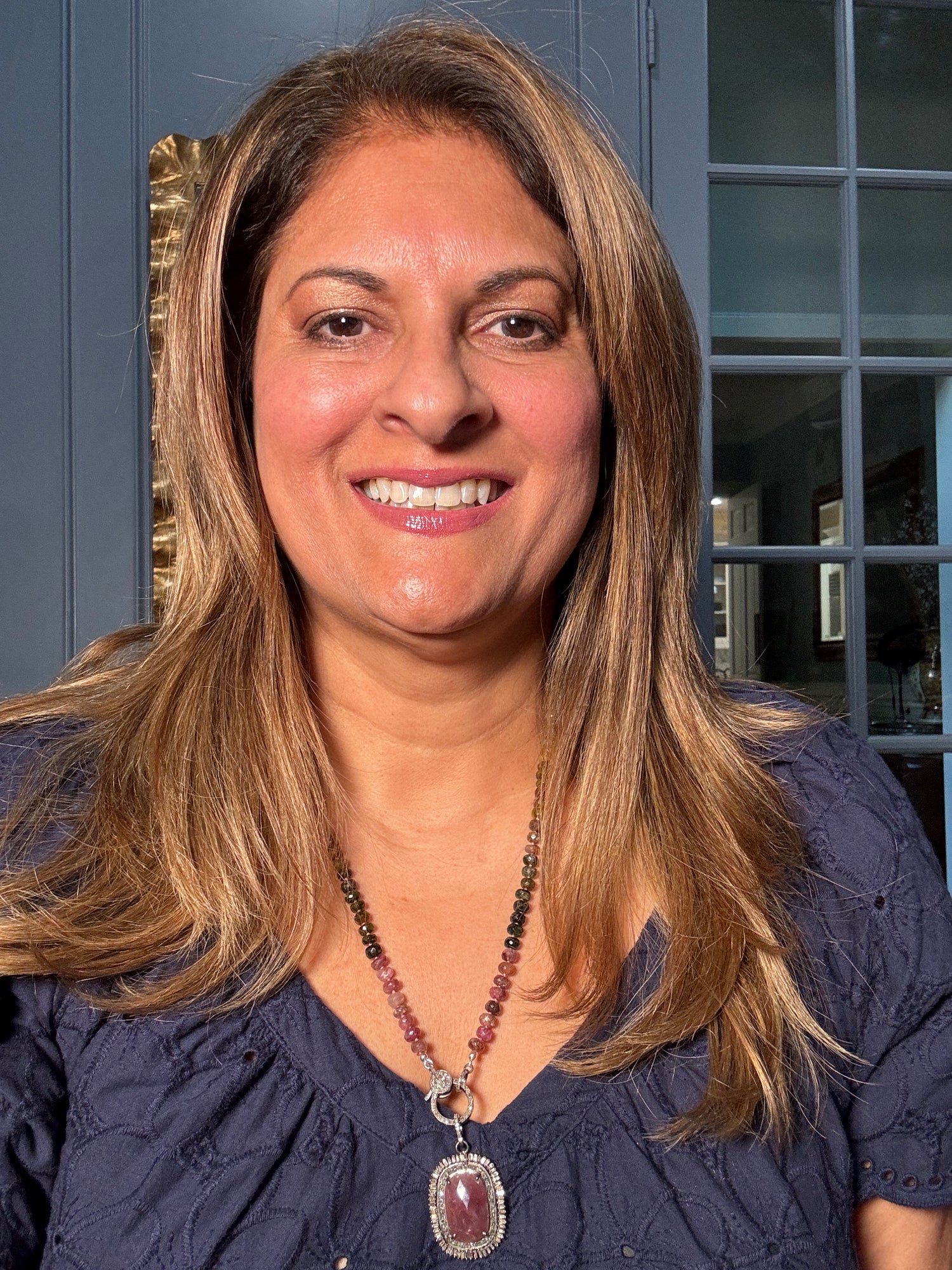 Woman wearing 24-inch multicolored tourmaline bead necklace featuring large ruby pendant with diamond halo setting and sterling silver clasp