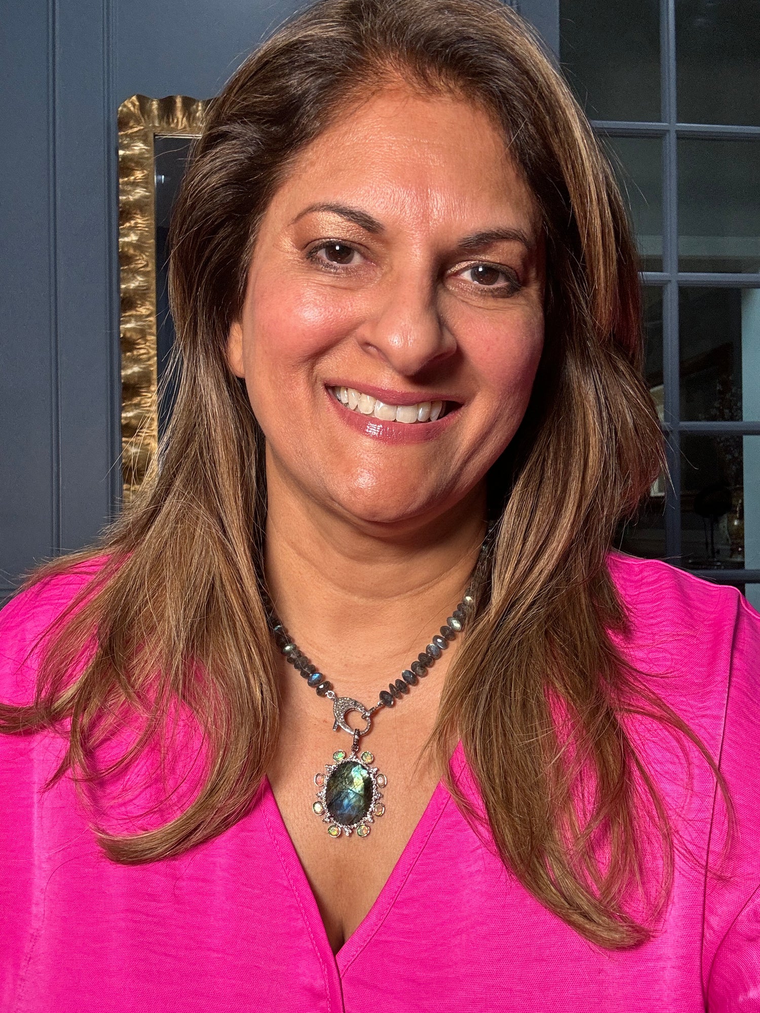 Woman wearing vibrant pink blazer showcasing 18-inch gray labradorite beaded necklace with ornate labradorite pendant featuring opal halo and diamond clasp