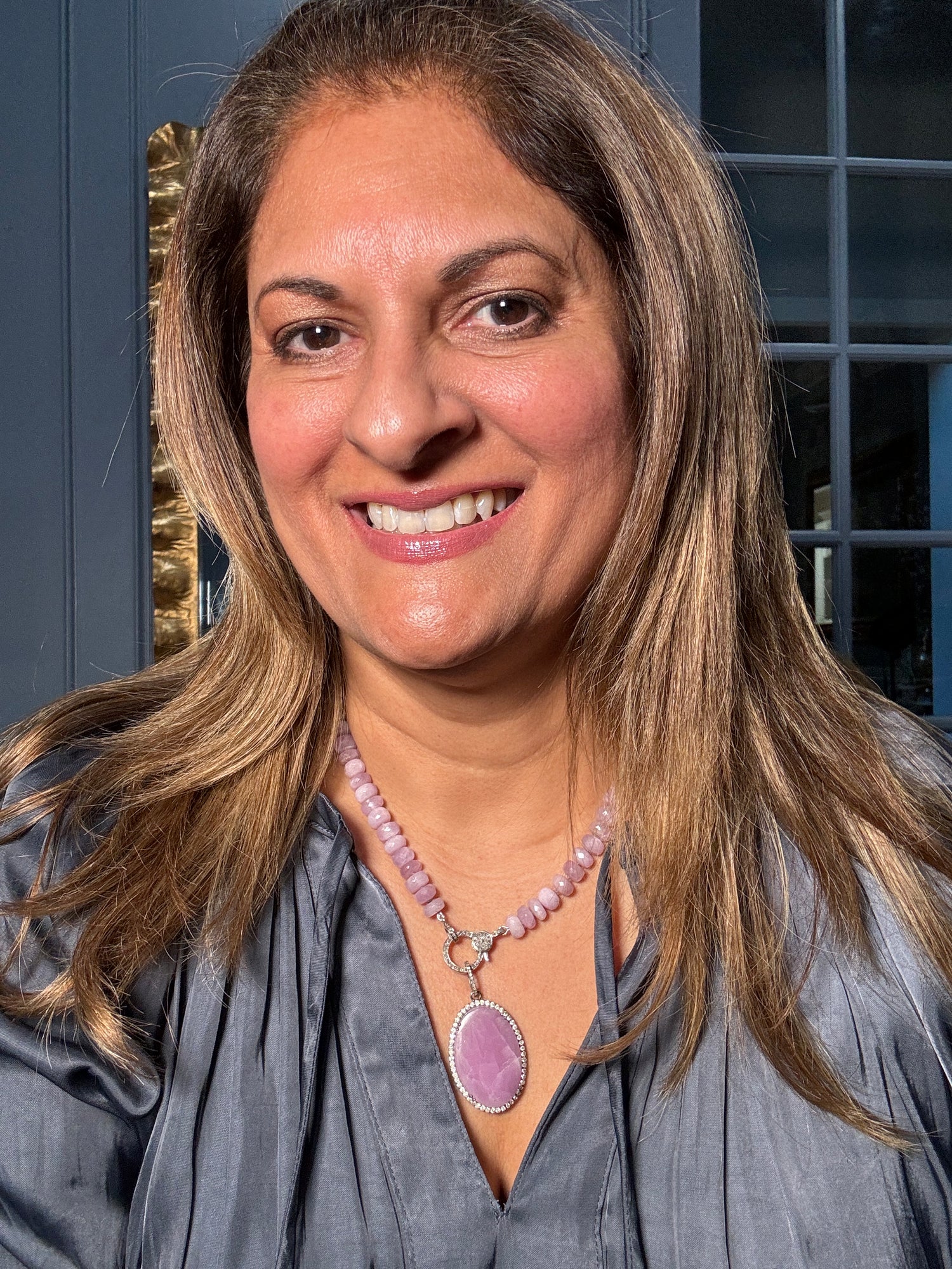 Woman wearing 19-inch lilac pink kunzite bead necklace with diamond-framed oval kunzite pendant against gray blouse