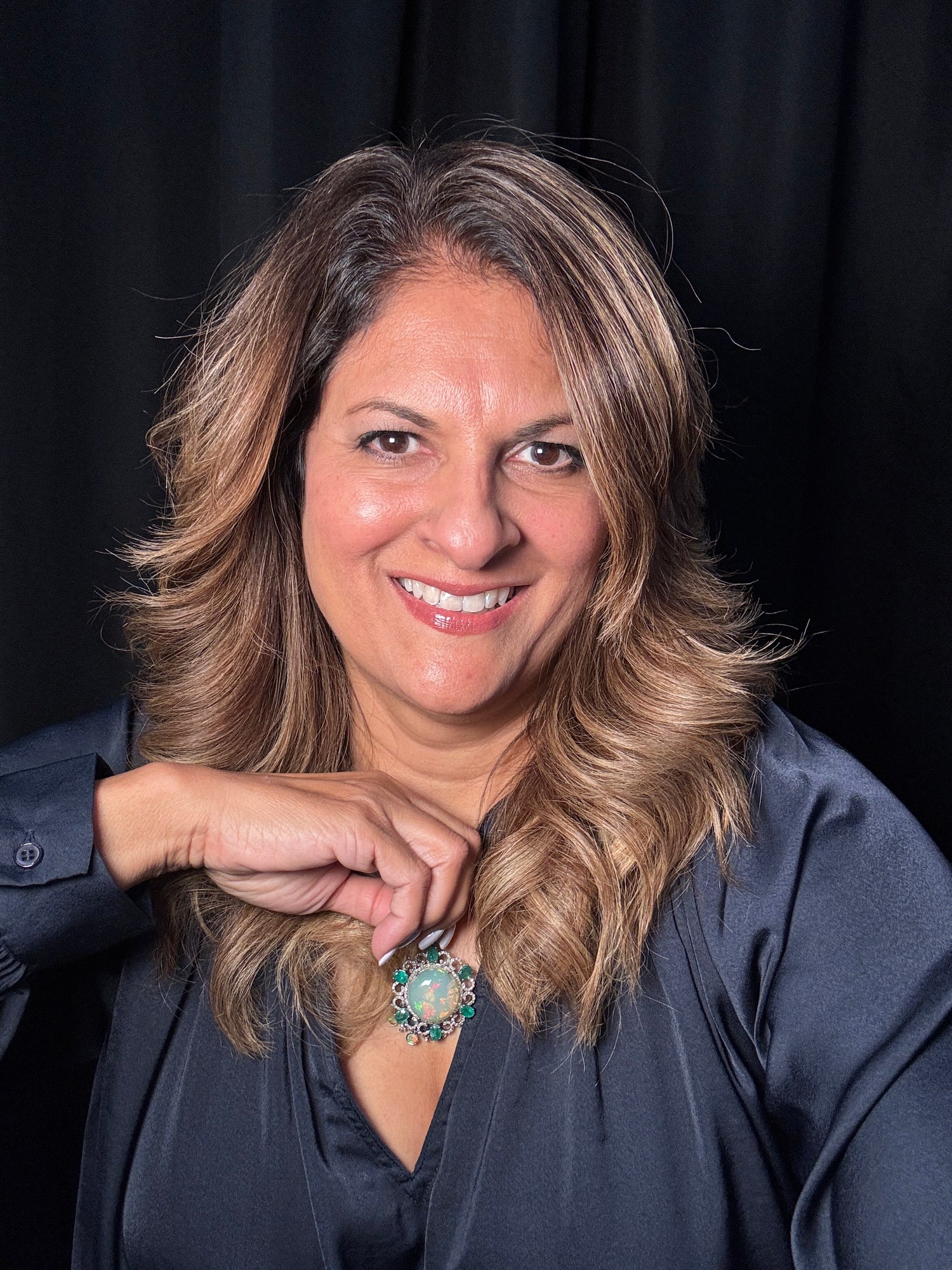 Woman wearing opal emerald diamond pendant on sterling silver chain, showing the colorful gemstone piece against dark navy shirt