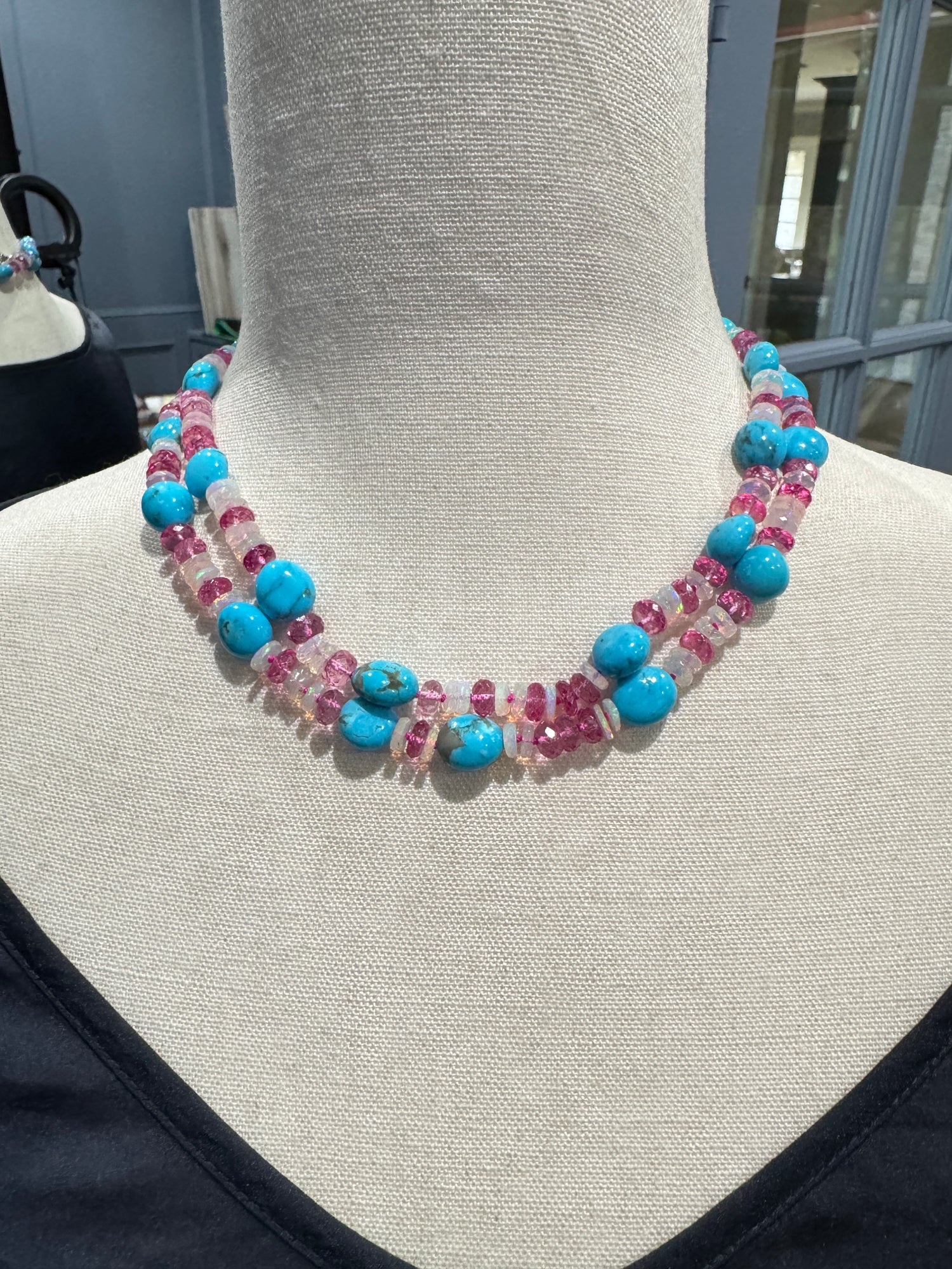 Long turquoise and pink gemstone necklace displayed on cream fabric mannequin showing the full 36-inch length and colorful bead pattern