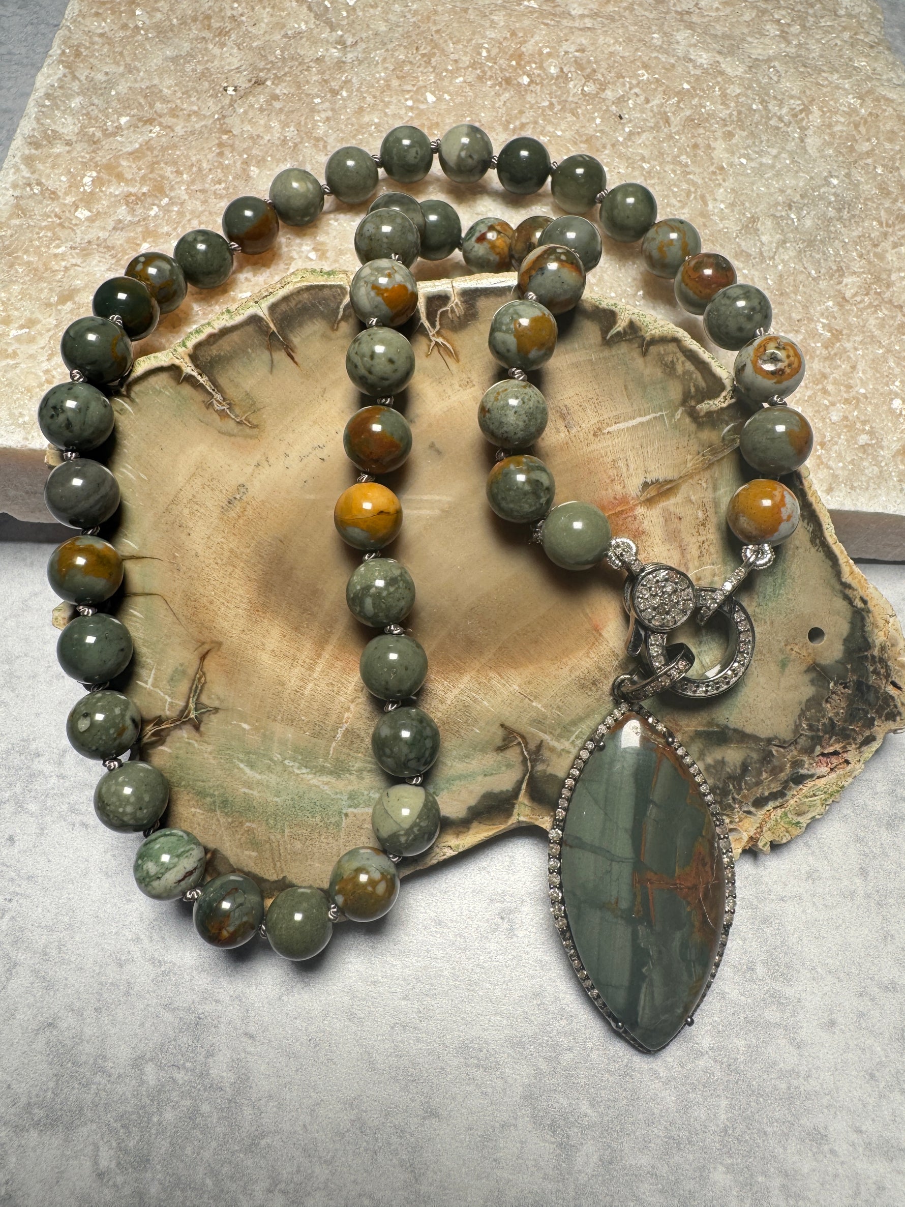 Full flat lay of Rocky Butte jasper necklace on petrified wood slice, displaying complete 18-inch length with diamond clasp and marquise pendant