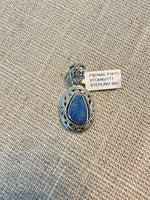Ornate sterling silver pendant with oval blue Australian opal in decorative twisted rope border setting, photographed on textured burlap background