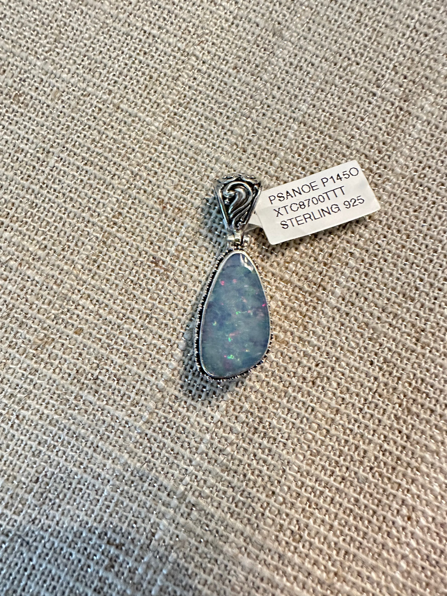 Elongated teardrop Australian opal pendant with blue-gray coloring and colorful flashes, set in minimalist sterling silver bezel mounting