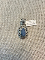Oval blue Australian opal in ornate sterling silver filigree setting with decorative scrollwork border, photographed flat on burlap fabric