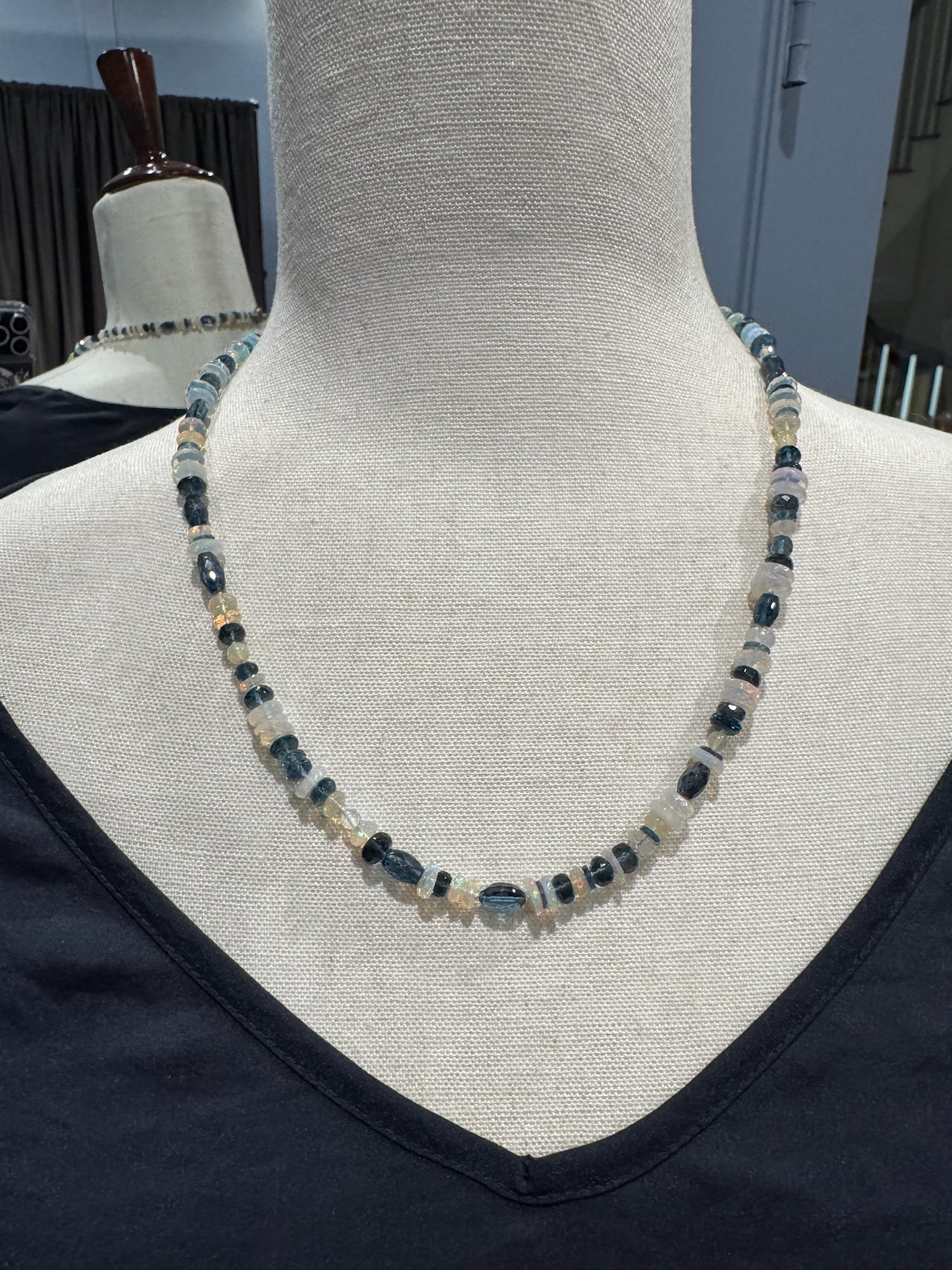 21-inch Ethiopian opal and London blue topaz necklace displayed on cream mannequin, showing alternating iridescent white opal discs and deep blue faceted topaz beads with sterling silver clasp