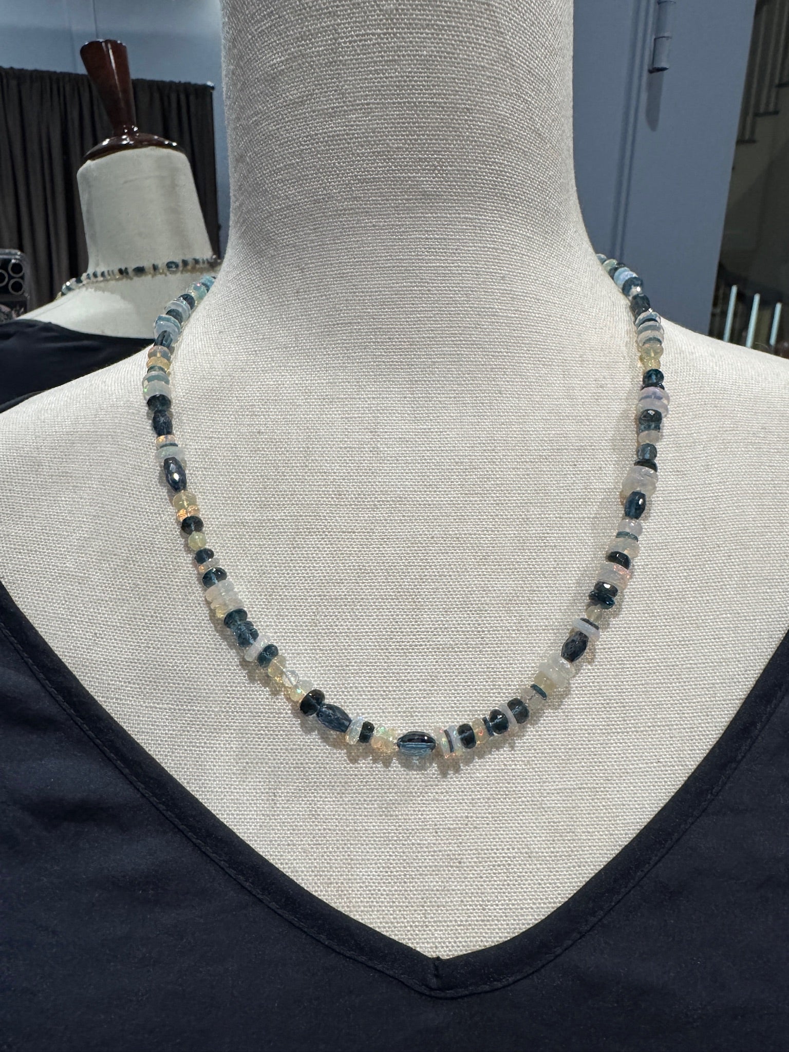 21-inch Ethiopian opal and London blue topaz necklace displayed on cream mannequin, showing alternating iridescent white opal discs and deep blue faceted topaz beads with sterling silver clasp