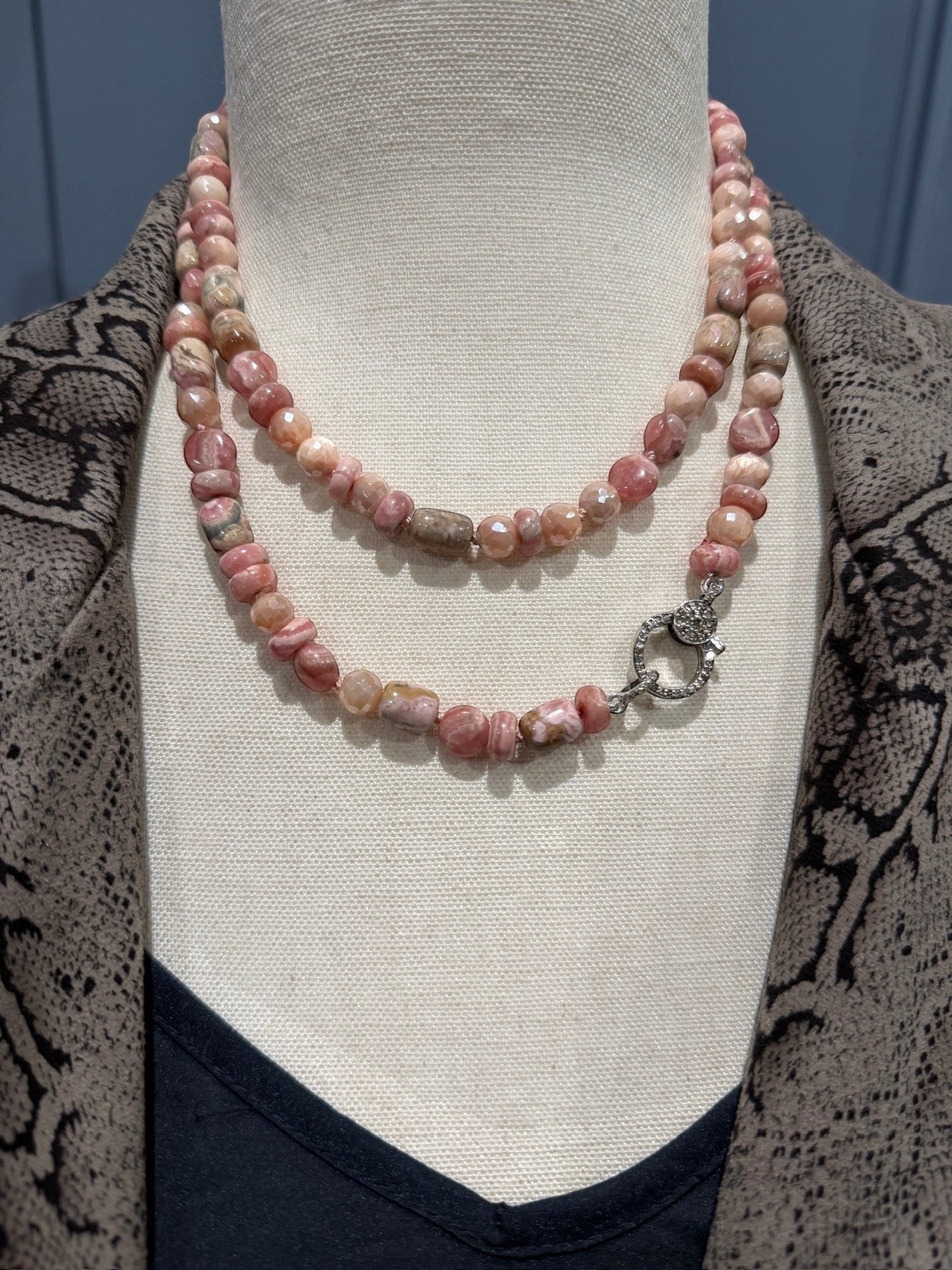 Long pink rhodochrosite and peach moonstone beaded necklace displayed on neutral mannequin, showing versatile layering styling