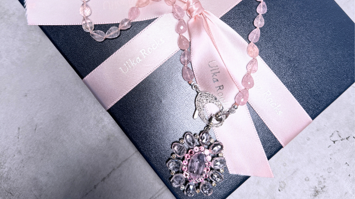 An Ulka Rocks gift box tied with a pink ribbon and rose quartz necklace