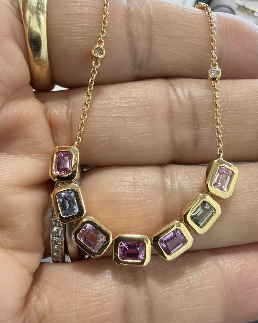 Seven emerald-cut sapphires in soft pinks, lavender, blue and green, set in 14k gold