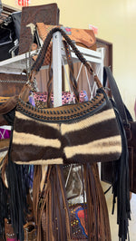 Zebra striped hair-on-hide fringe bag with black studs and whipstitch trim