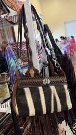 Zebra striped hair-on-hide crossbody bag with black studded top band and silver concho